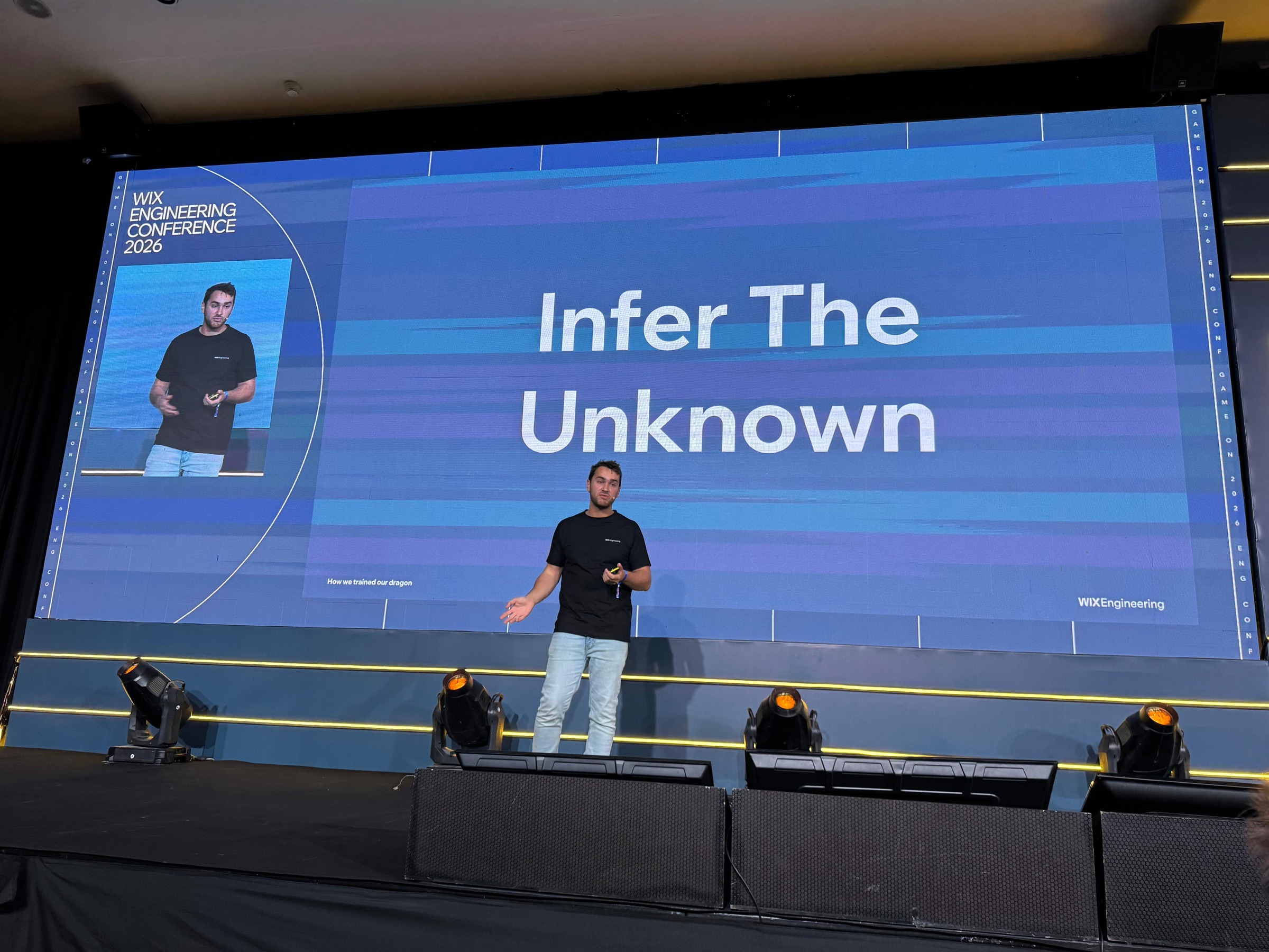 David Gahnassia on stage at Wix Engineering Conference 2026, with 'Infer The Unknown' shown on the huge screen behind him